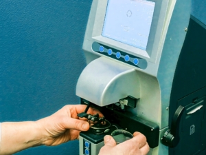 Zwei Hände arbeitenmit einem Objektträger unter einem Laborgerät mit Folientastatur.